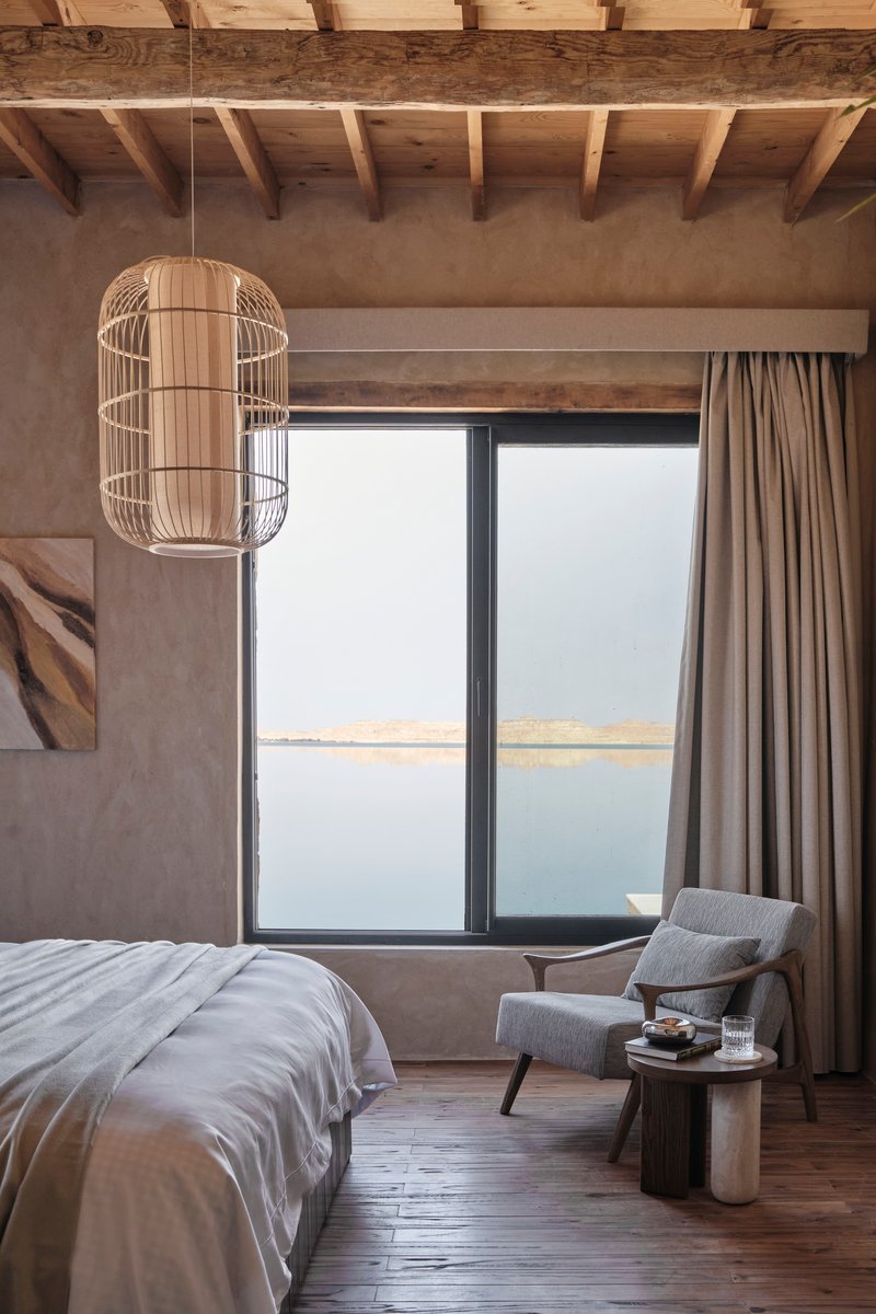 Bedroom interior with exposed timber ceiling joists and a cage pendant light beside the window