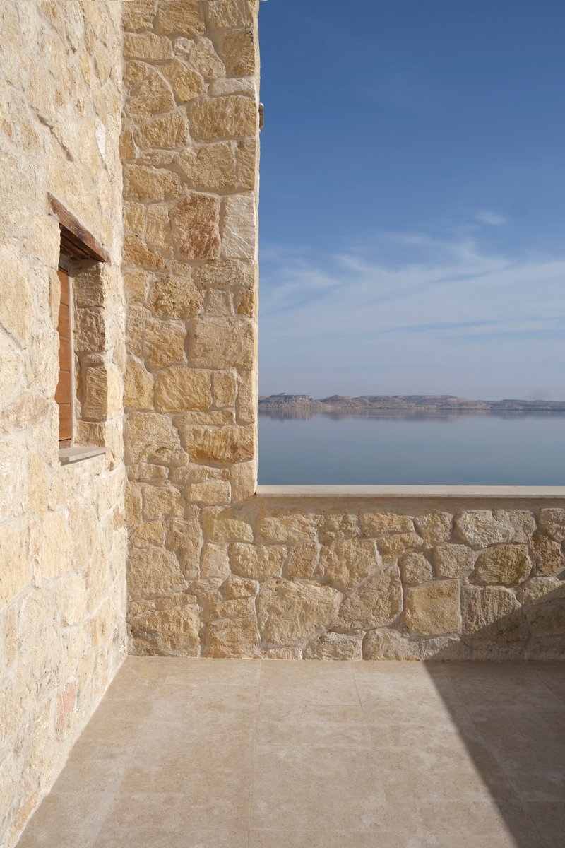 Corner terrace with limestone walls overlooking calm water under clear blue sky