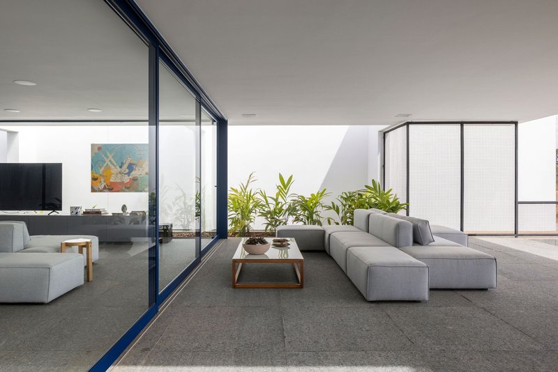 Living room with grey sectional sofa and floor-to-ceiling glazing opening to planted courtyard