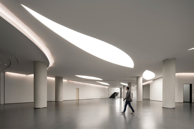 Lobby with curved skylights cutting through the ceiling as a visitor walks across polished floor