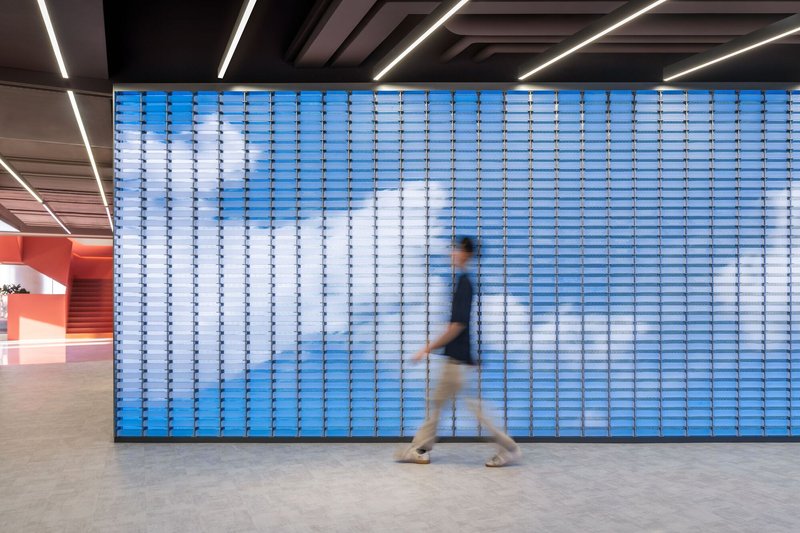 Backlit blue translucent glass block wall with a person walking past in motion blur