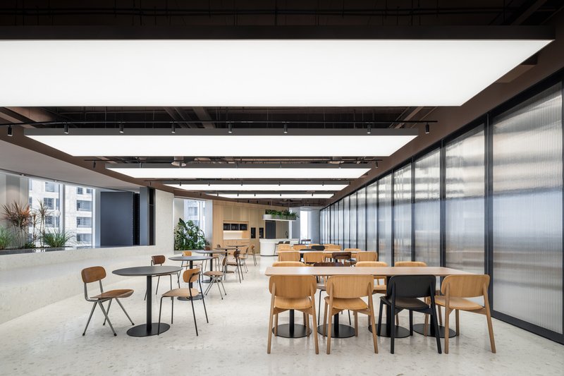 Cafe area with scattered tables and chairs next to floor-to-ceiling translucent glass partitions