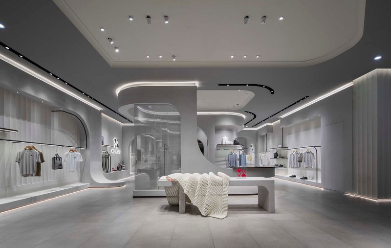 Interior of a retail space with curved white ceiling elements, recessed linear lighting, and central display table