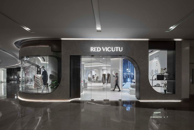 Glass storefront with curved vitrine and polished dark floor reflecting the illuminated display windows