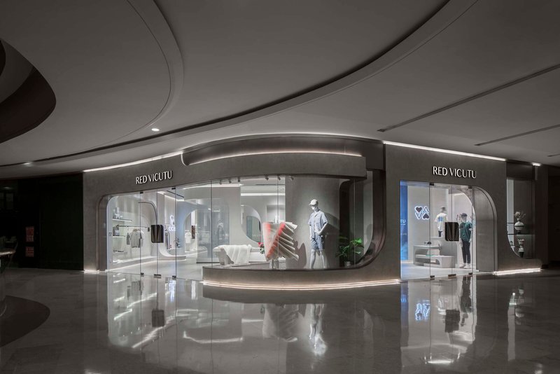 Storefront facade with curved glass and gray stone surround reflected in the glossy mall floor