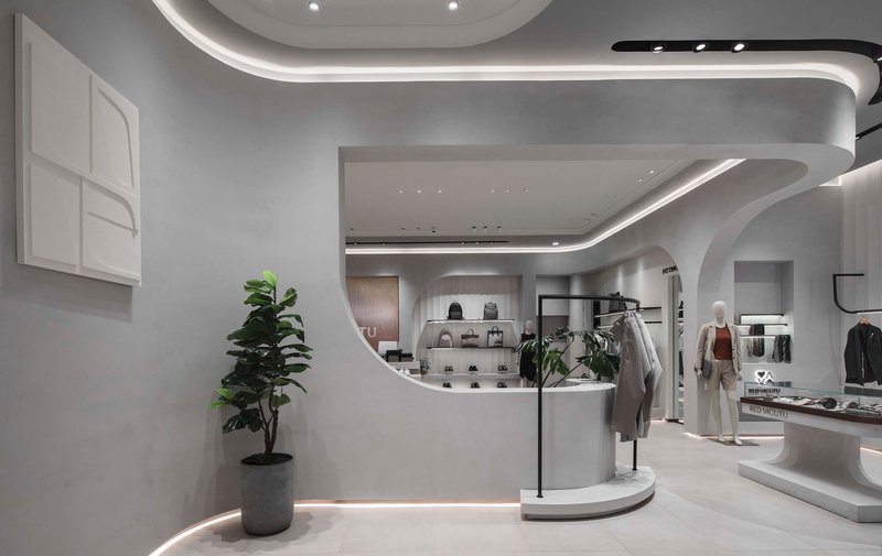 View toward the curved display counter with a potted fiddle-leaf fig beside the white partition wall