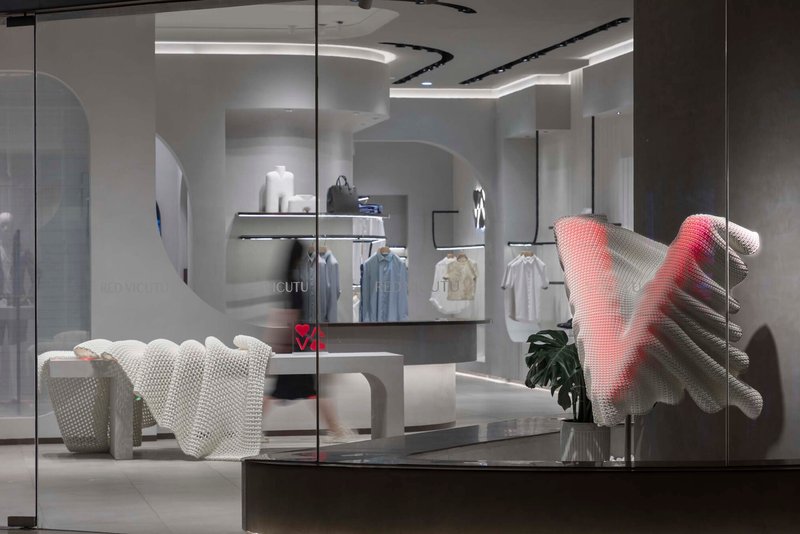 View through glass storefront showing textured seating and undulating ceiling cove with integrated lighting