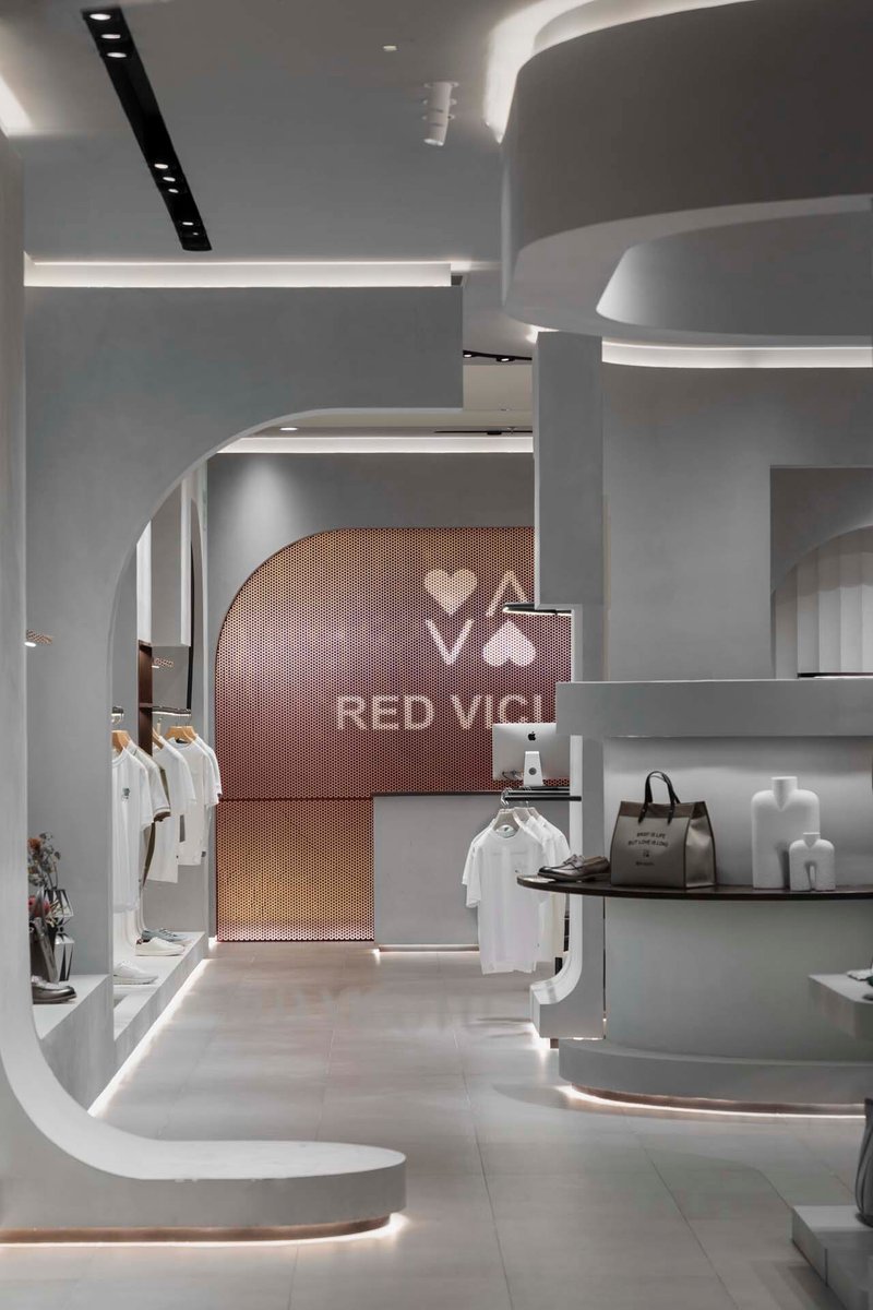 Arched portal with copper mesh screen backdrop connecting retail zones with curved white millwork