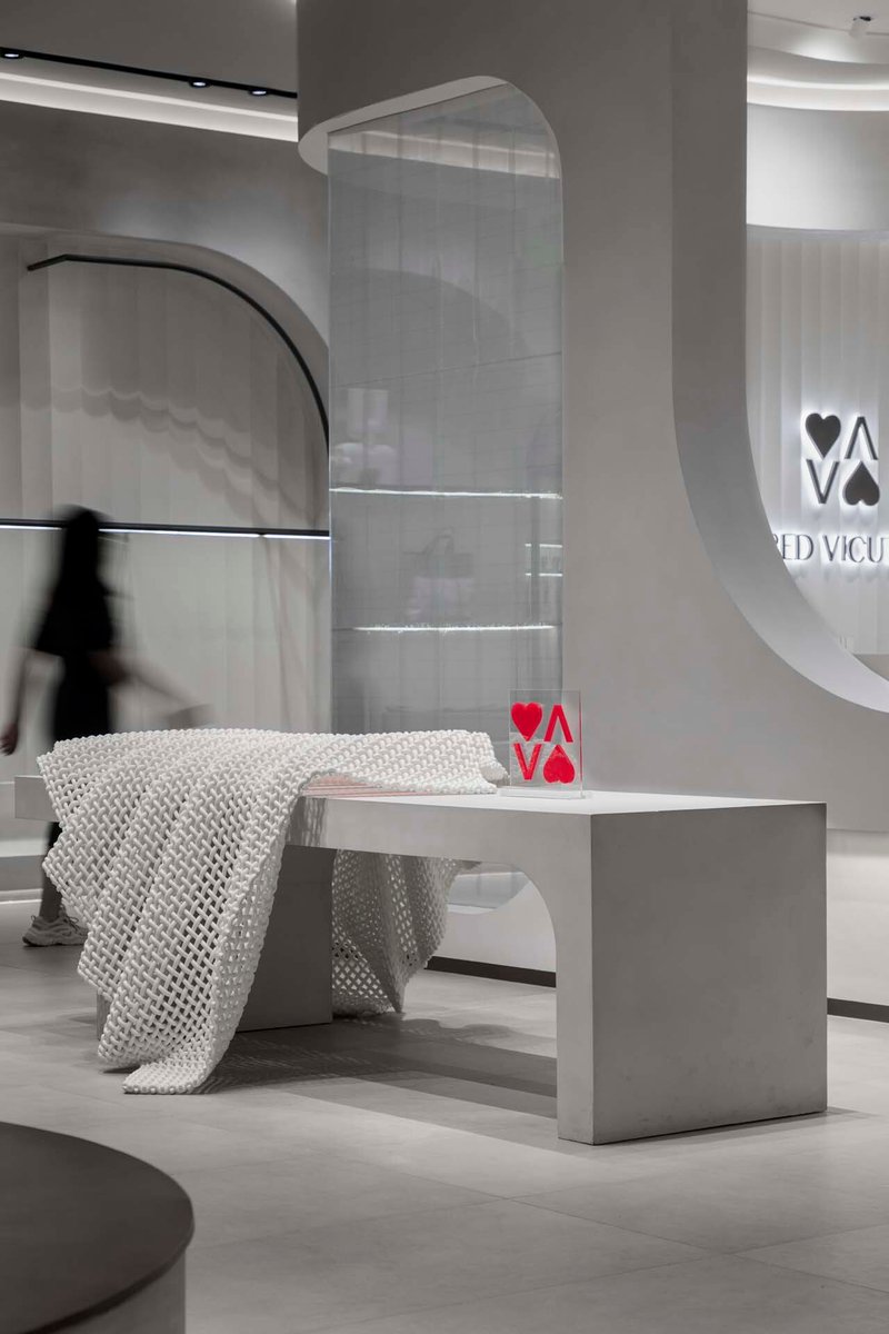 White bench draped with textured throw beside curved wall and person in motion