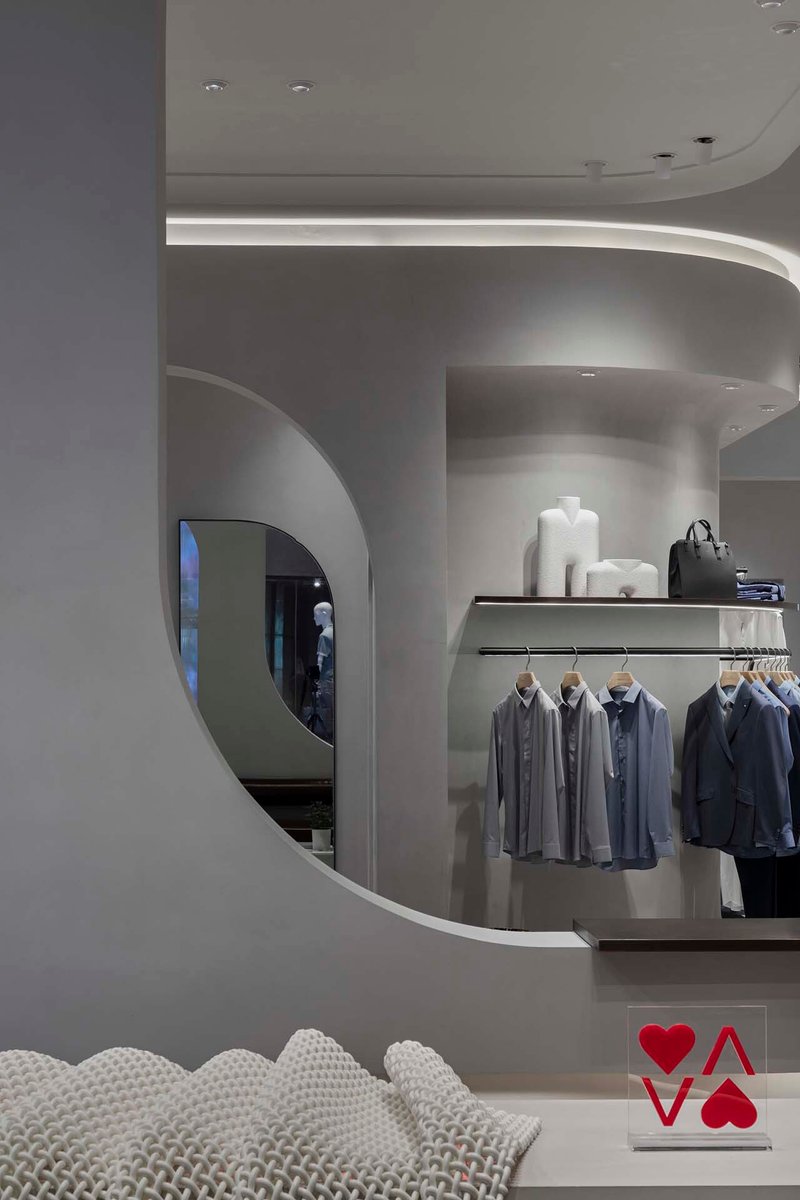 View through curved archway into retail space with recessed cove lighting above rounded walls
