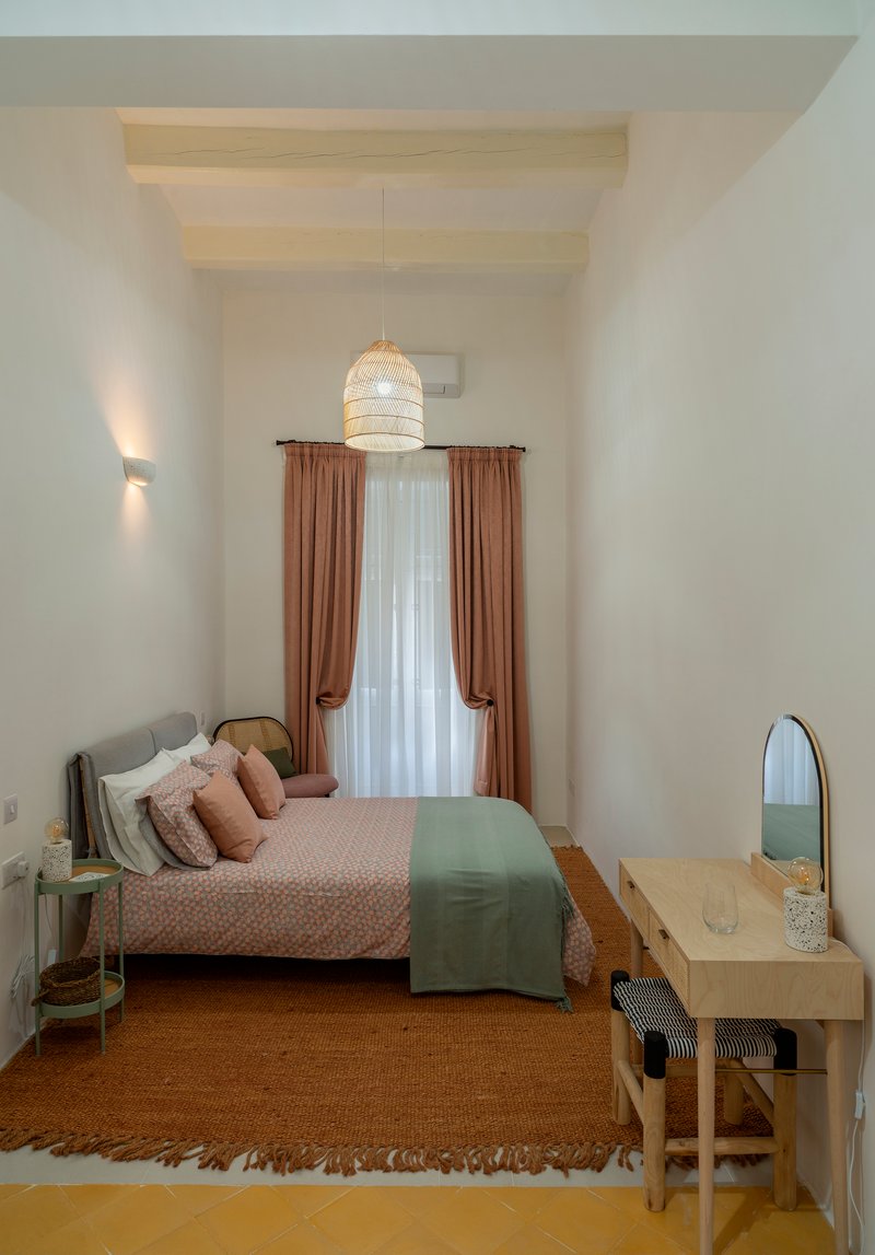 Bedroom with exposed timber ceiling beams and a woven pendant light above the bed