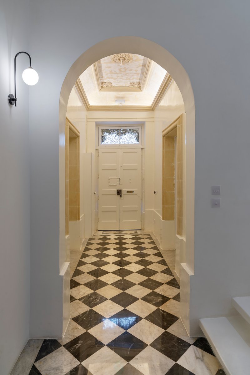 Entry hall viewed through an arch with checkerboard marble flooring and a skylight above