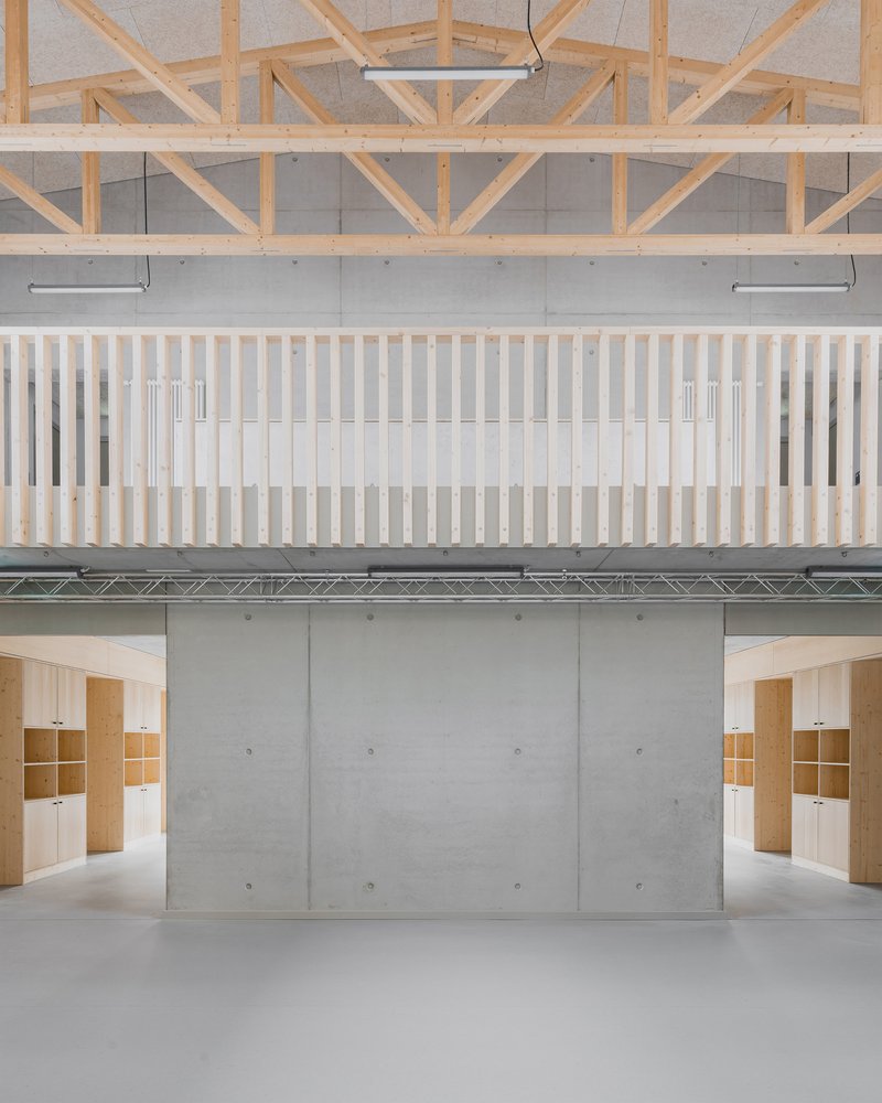 Vertical batten balustrade overlooking concrete wall with plywood shelving units below timber truss ceiling