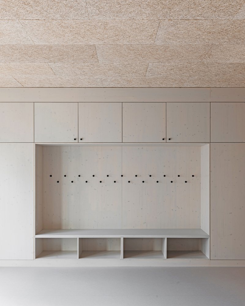 Built-in mudroom alcove with plywood panels, coat hooks, and cubby storage below