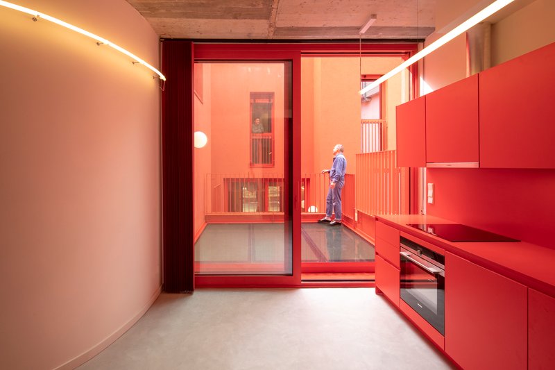 Kitchen with red cabinetry and sliding glass door opening to a terrace with timber ceiling