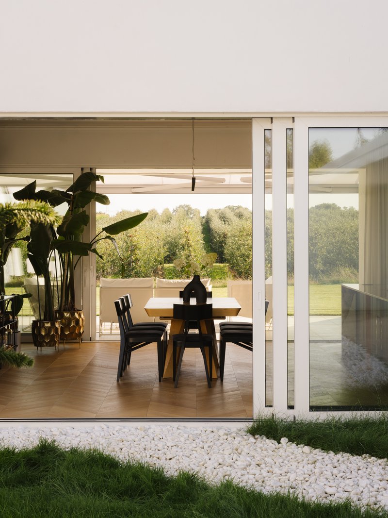 Glazed corner opening onto the dining area with timber flooring and a white pebble garden bed