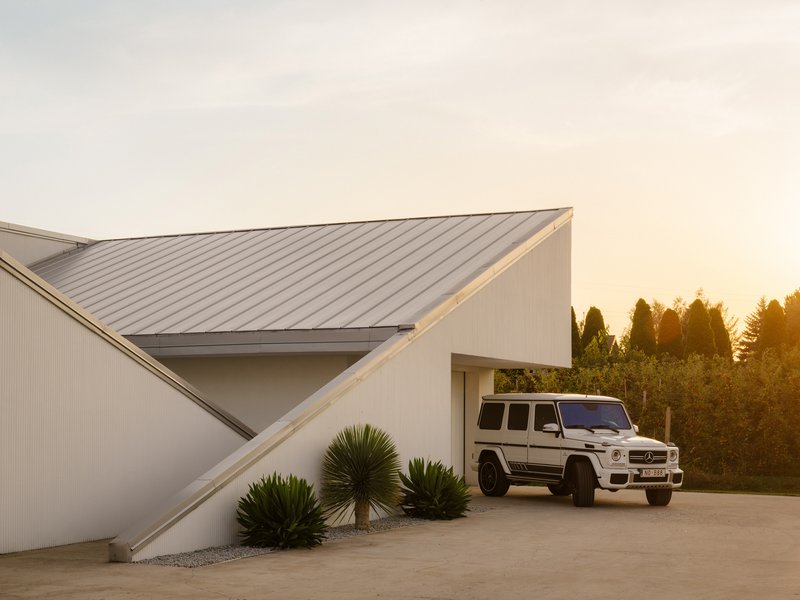 Entry courtyard with standing seam metal roof planes and vehicle parked at dusk