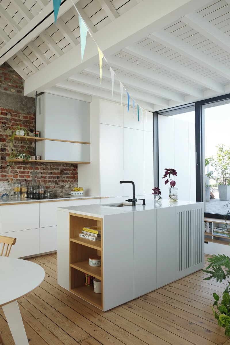 Kitchen island with integrated shelving and fluted panel detail beneath a white painted beam ceiling