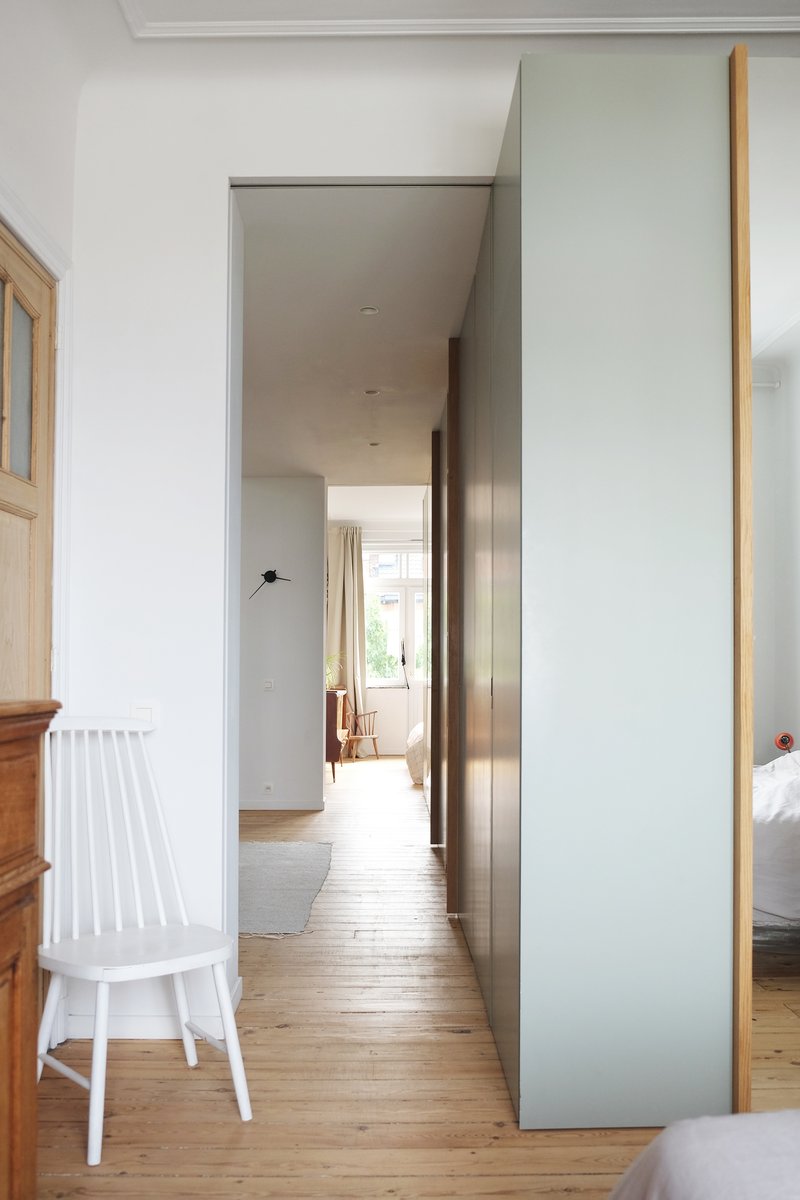 Interior hallway framed by grey panels with timber edging and light-filled passage leading to distant rooms