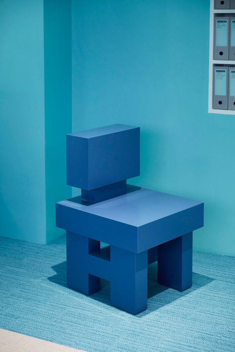 Geometric chair form with rectangular seat and back in solid blue against a corner