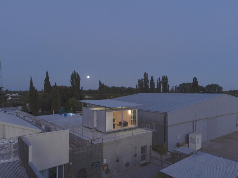 Elevated rooftop pavilion with glass walls and timber cladding at dusk with moon rising
