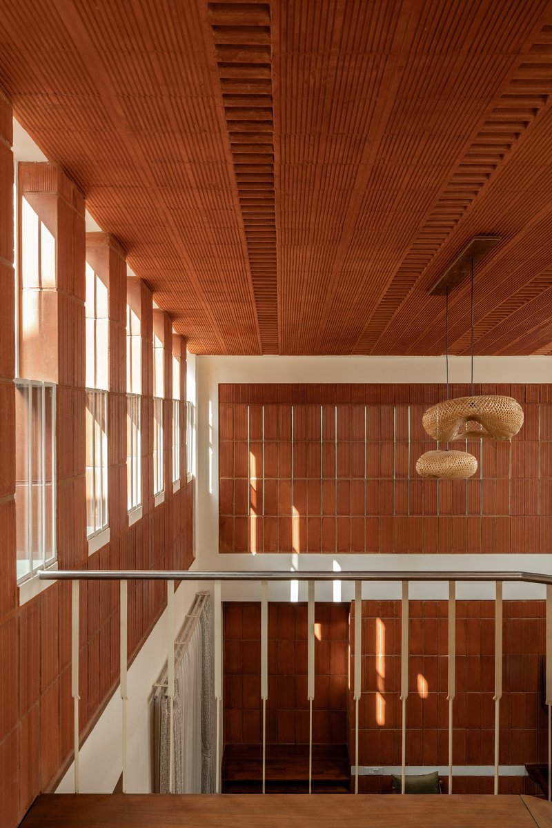 Double-height atrium with timber-slatted ceiling and wall panels flooded with afternoon sunlight