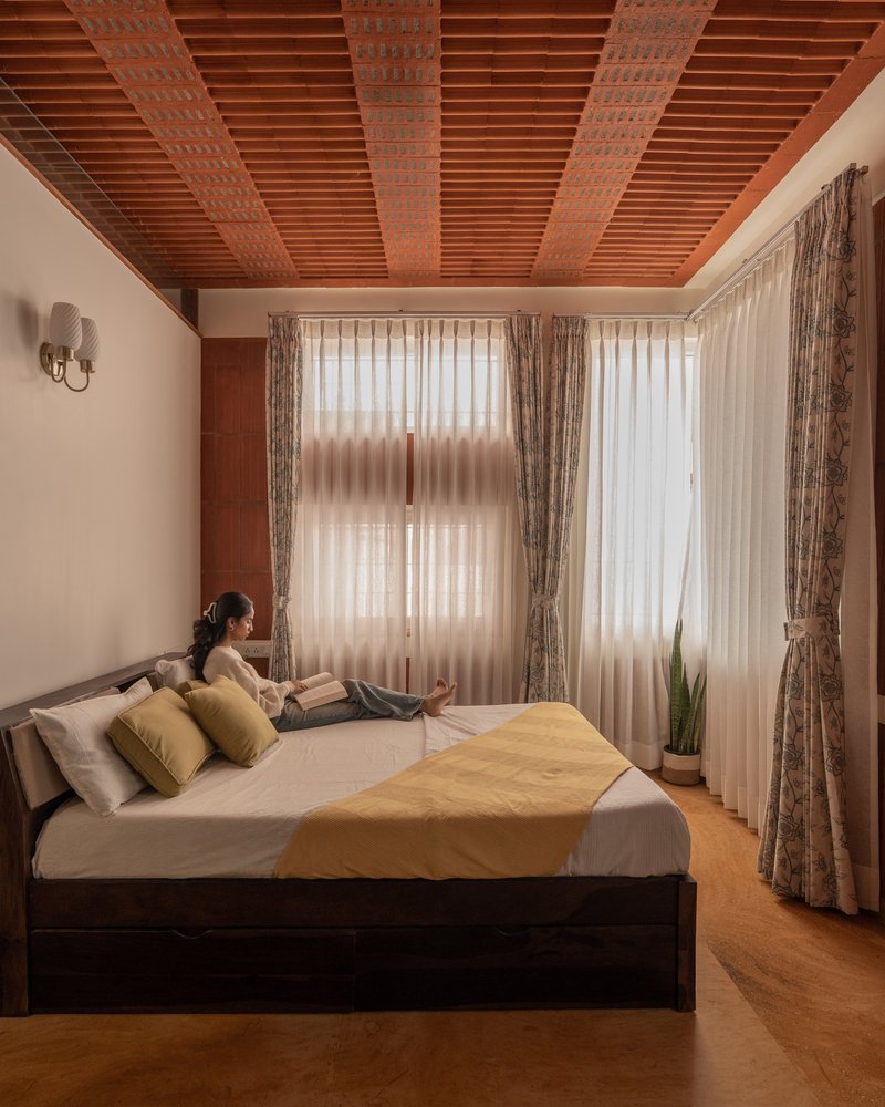 Bedroom with timber-slatted ceiling and sheer curtains diffusing soft morning light