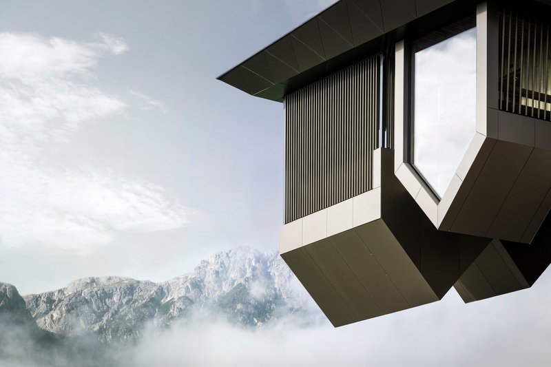 Corner detail of the faceted volume with vertical metal slats floating above misty alpine ridges