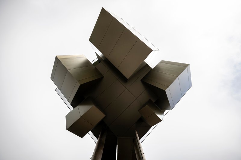 Underside view showing the cruciform arrangement of cantilevered metal-clad volumes meeting at a central support
