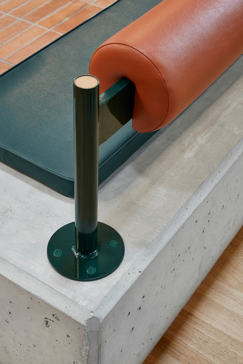Close-up of tubular steel armrest support anchored to a concrete plinth base