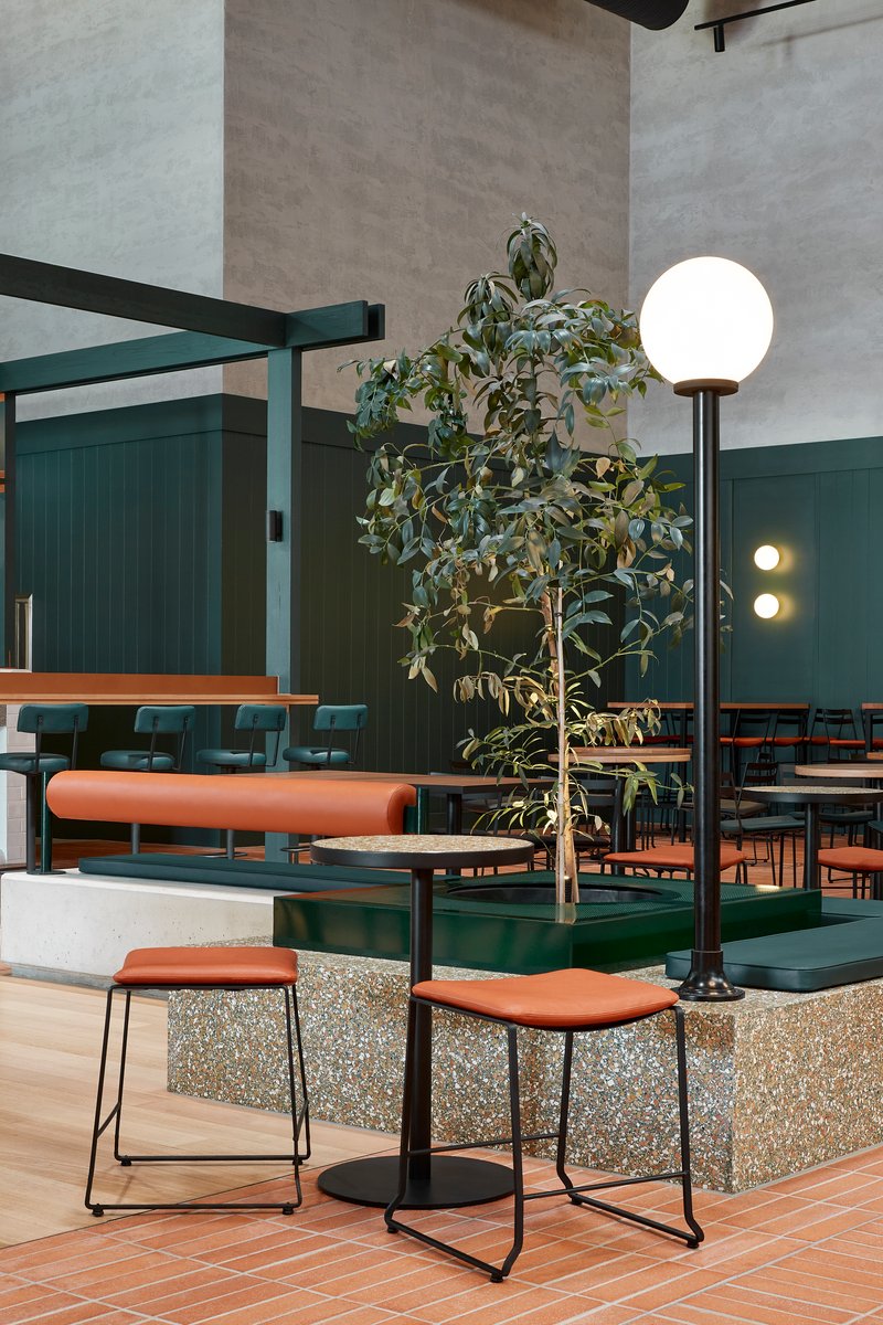 Raised terrazzo platform with bar stools and potted tree beneath a globe floor lamp