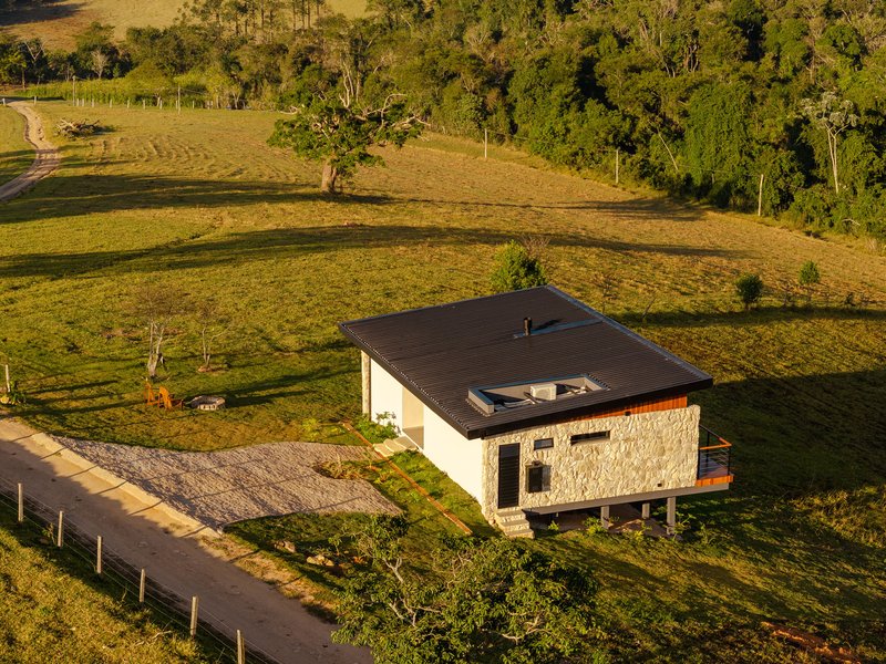 Aerial view of the single-story residence with stone and white plaster walls set in rolling grassland at dusk