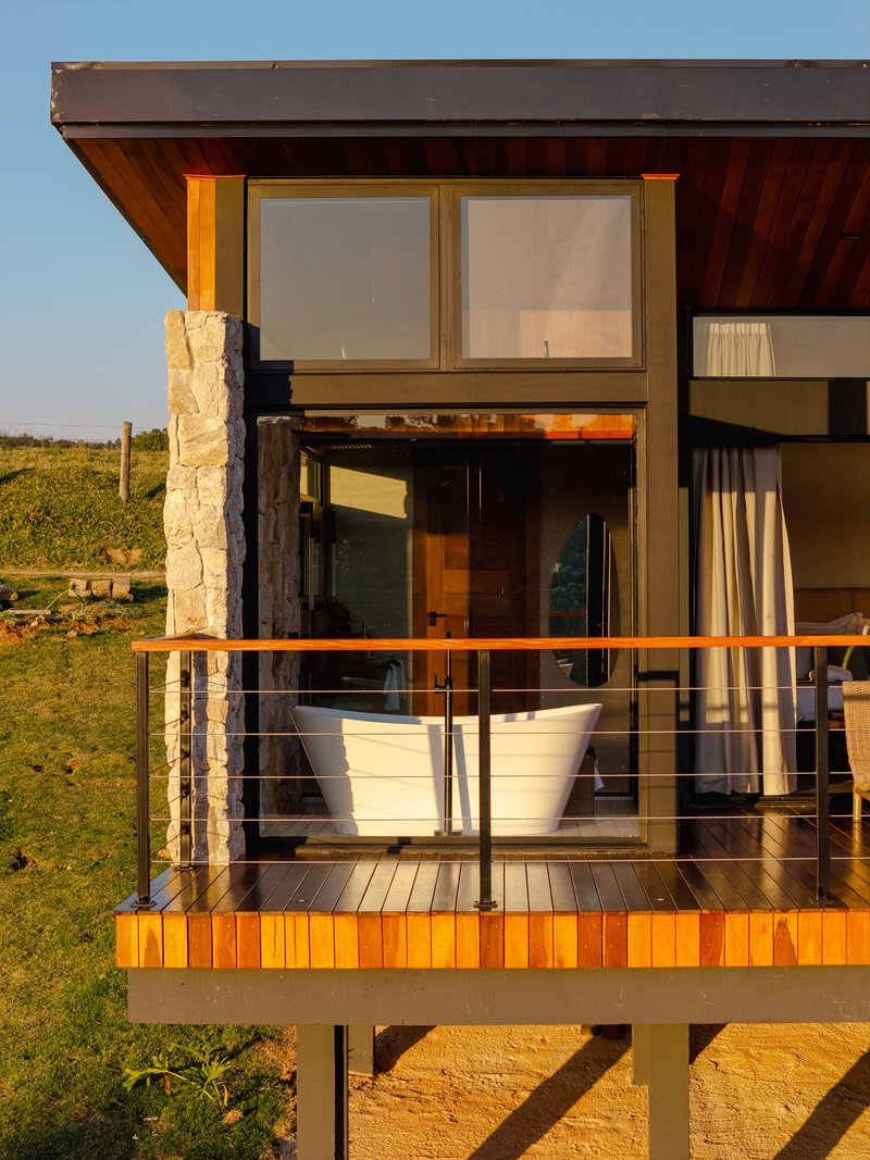 Cantilevered timber deck with cable railing and stone chimney bathed in late afternoon sunlight