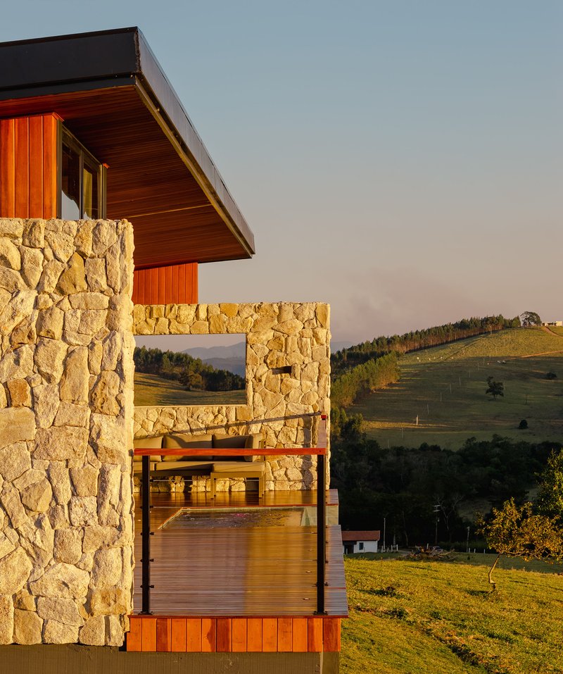 Stacked stone walls framing the open terrace with wooden soffit overhang at sunset
