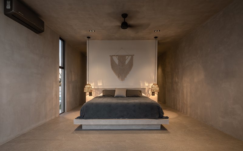 Bedroom with polished concrete platform bed and recessed illuminated alcove behind the headboard