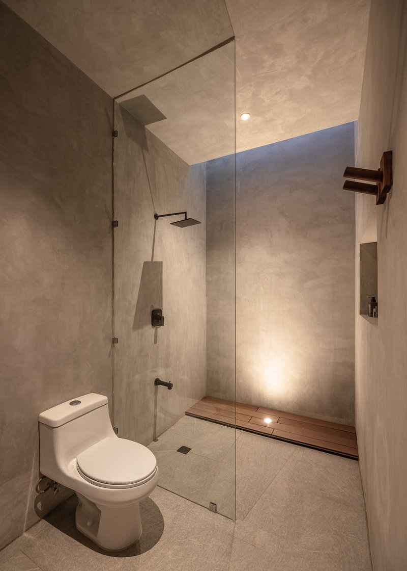 Bathroom with glass-enclosed shower area, wall-mounted toilet and skylight slot above