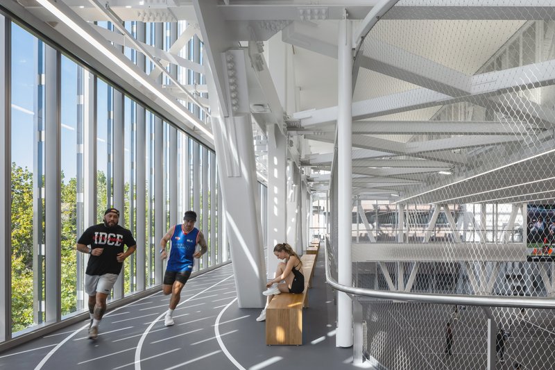 Interior running track with vertical white fins and white structural columns in bright daylight