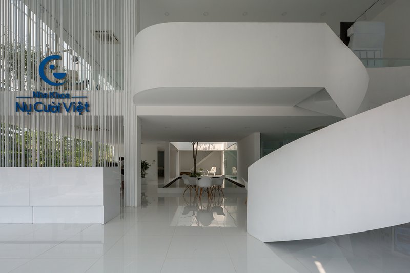 Reception area with curved white sculptural volume wrapping around a central courtyard with a tree