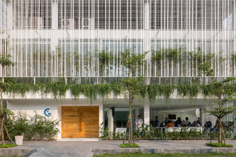 Street-level facade with vertical white slat screen above ground floor entrance and planted terrace with cascading vines