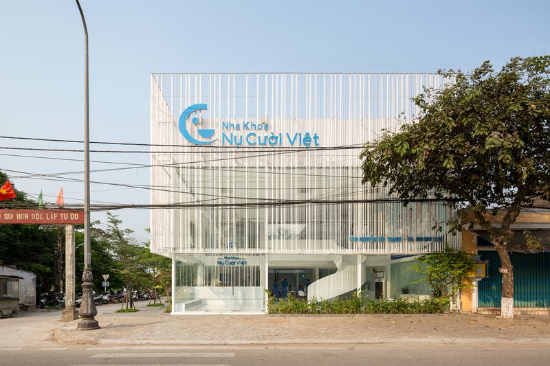 Front elevation showing vertical white screening system and planted layers viewed from the street with overhead wires