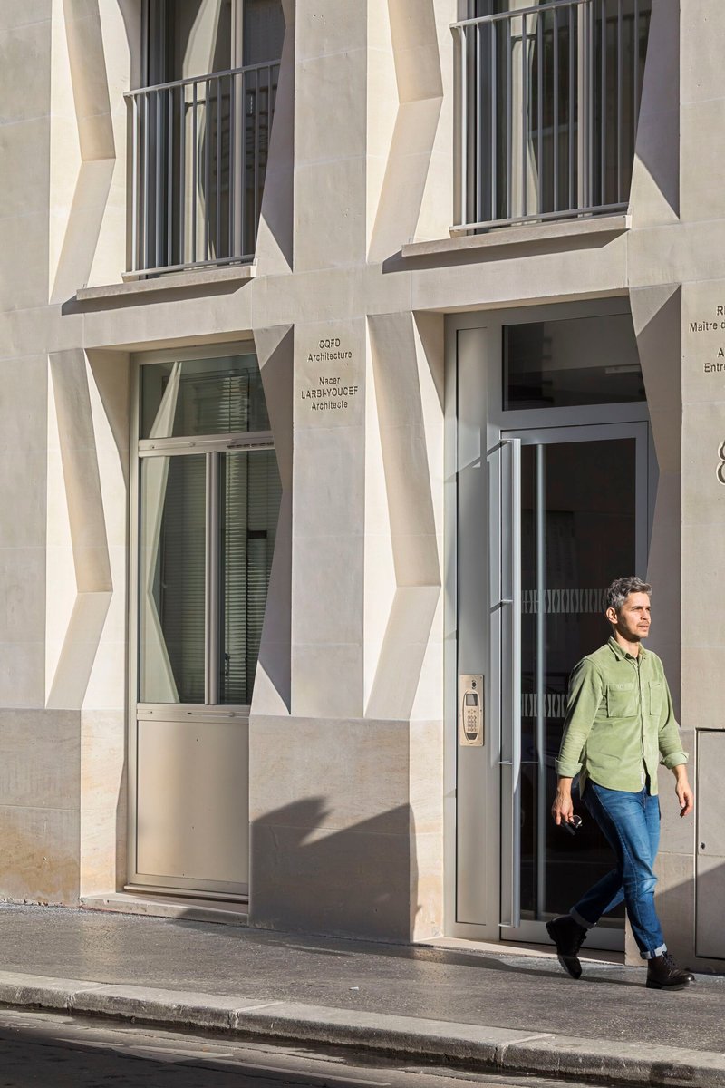 Ground-level entry with glass door as a person in green shirt exits onto the sidewalk
