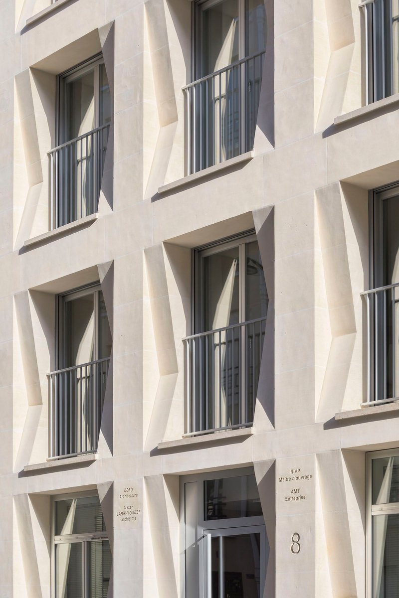 Facade detail showing stacked balconies with metal railings set within diagonal precast frames