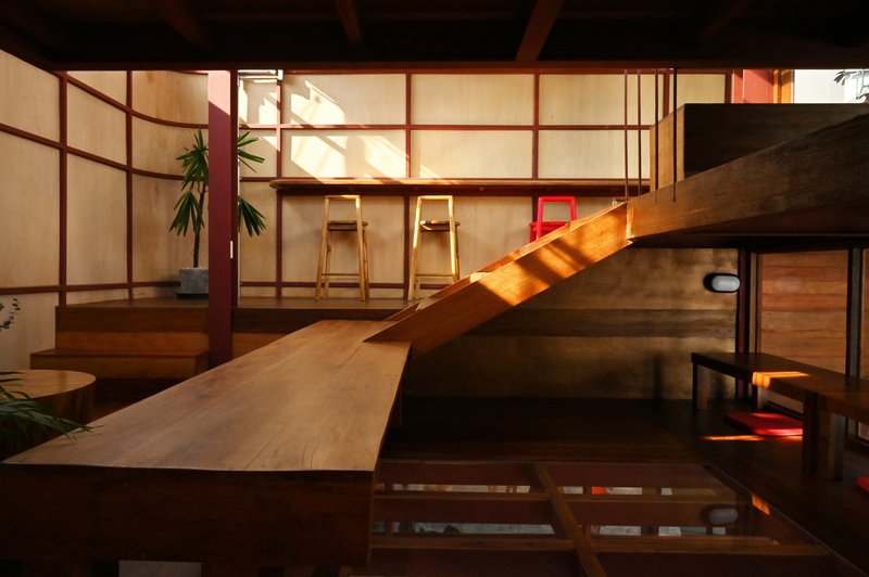 Interior view of timber stair rising alongside translucent screen panels with warm evening lighting