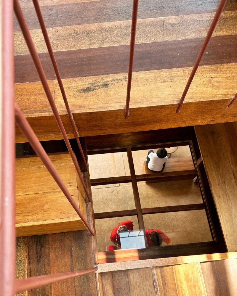 Looking down through floor opening with steel railing as two people sit at table below
