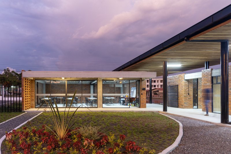 Green roof courtyard with glass-walled dining area and landscape lighting under a purple twilight sky