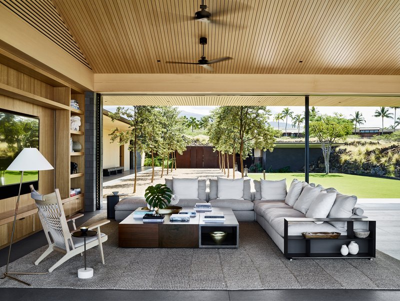 Living area with slat wood ceiling opening through glass walls to planted courtyard beyond