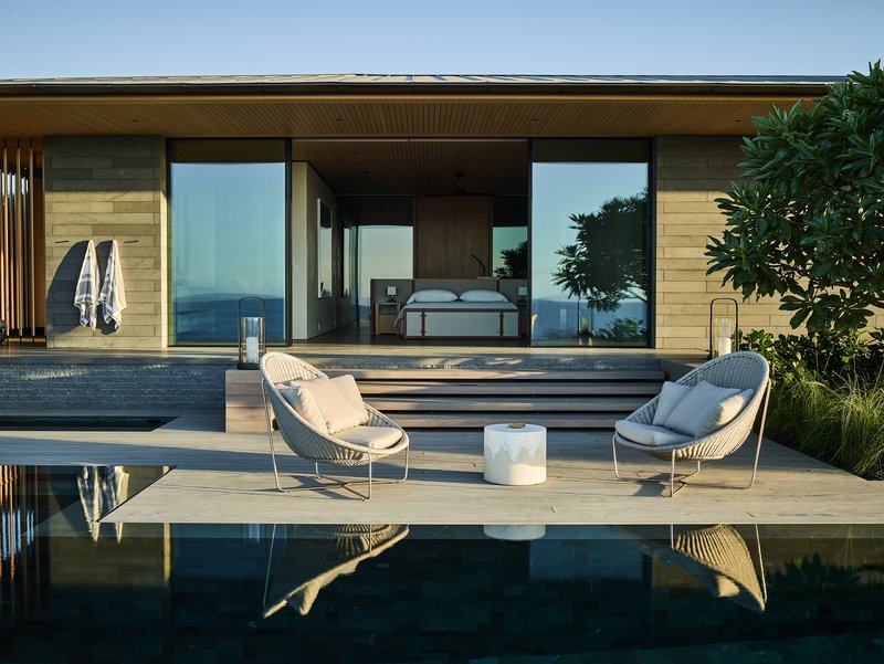 Poolside terrace with timber decking and slatted ceiling opening to a bedroom with ocean views