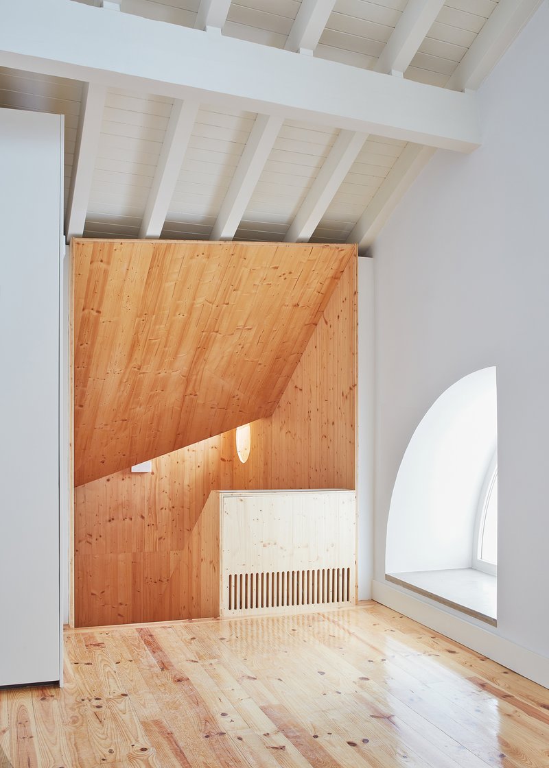 Timber-lined passageway with arched window seat and exposed ceiling beams above