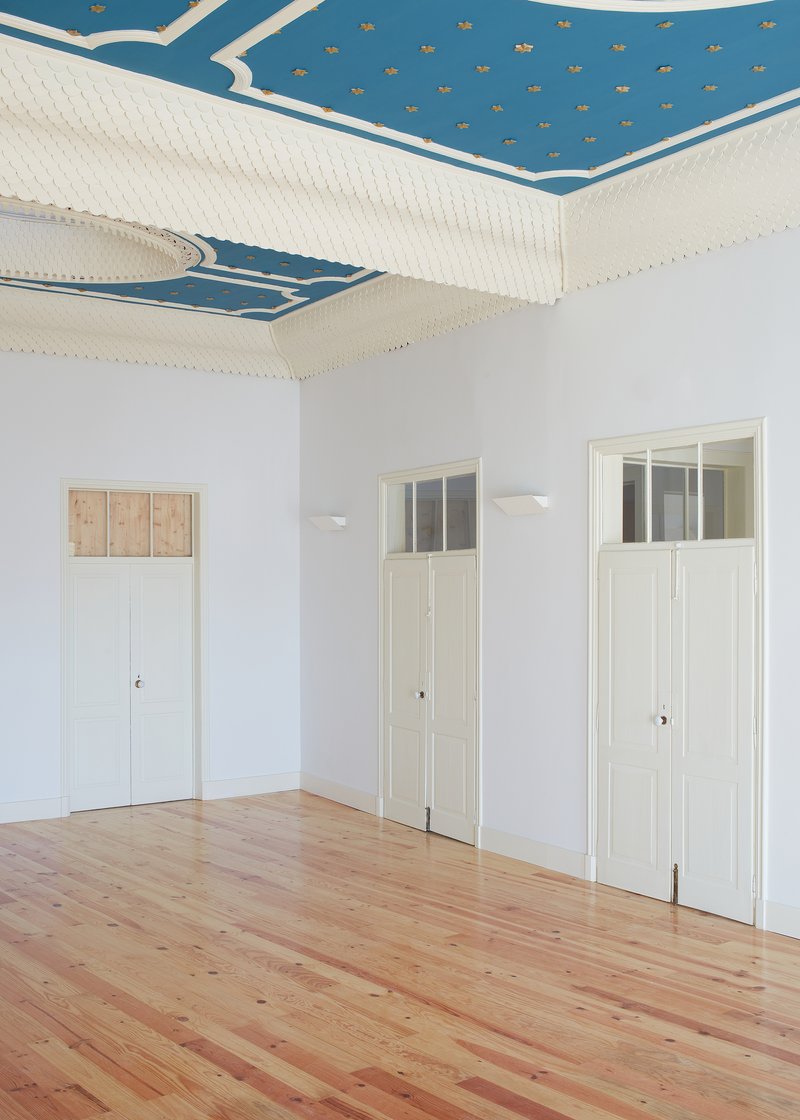 Three tall doors with transom windows beneath restored blue and gold painted ceiling with star pattern