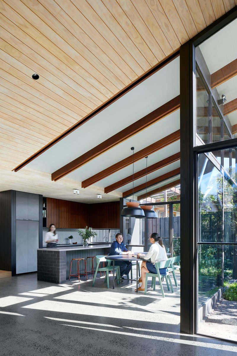Open-plan kitchen and dining area with exposed timber beams and two people seated at a table